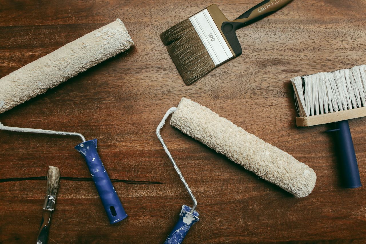 Crafting Captivating Headlines: Your awesome post title goes here Top view of various painting tools including rollers and brushes laid out on a wooden surface.