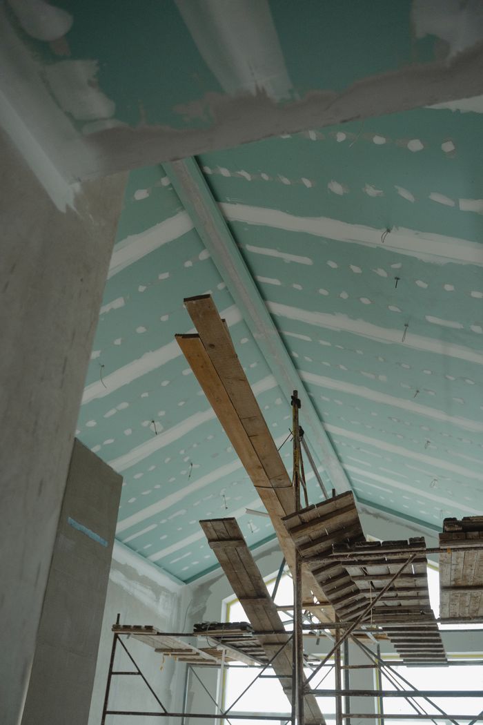 Réalisations Scaffolding setup in an interior construction space with suspended ceiling boards and wooden planks.